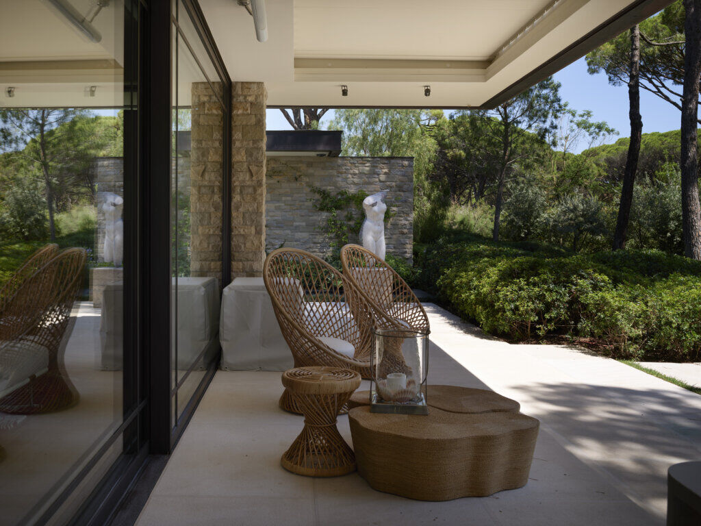 Outdoor Lounge with Fabio Viale Sculpture — Saint-Tropez Villa Outdoor terrace with Bonacina woven chairs and a Fabio Viale marble sculpture, surrounded by Mediterranean greenery in Primadesign’s Saint-Tropez villa.