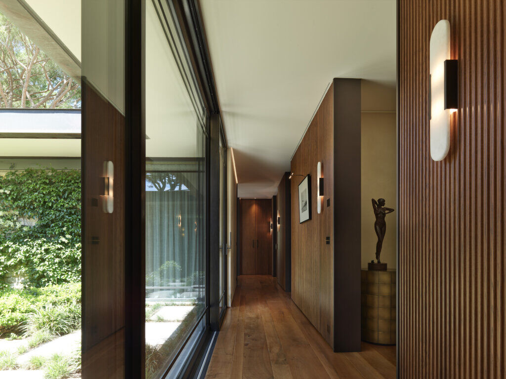 Wooden Corridor with Seamless Indoor–Outdoor Connection — Saint-Tropez Villa Hallway of a luxury villa in Saint-Tropez designed by Primadesign, featuring vertical wooden paneling, floor-to-ceiling glass, and a fluid connection between interior architecture and the Mediterranean garden.