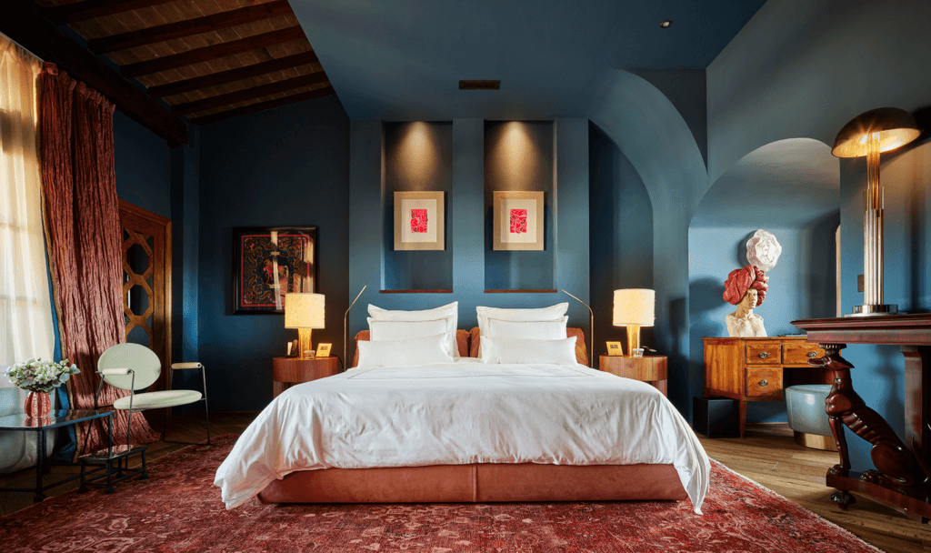 Luxury suite with organic architecture, blue and red complementary tones, and warm lighting at The James Hotel, Florence.